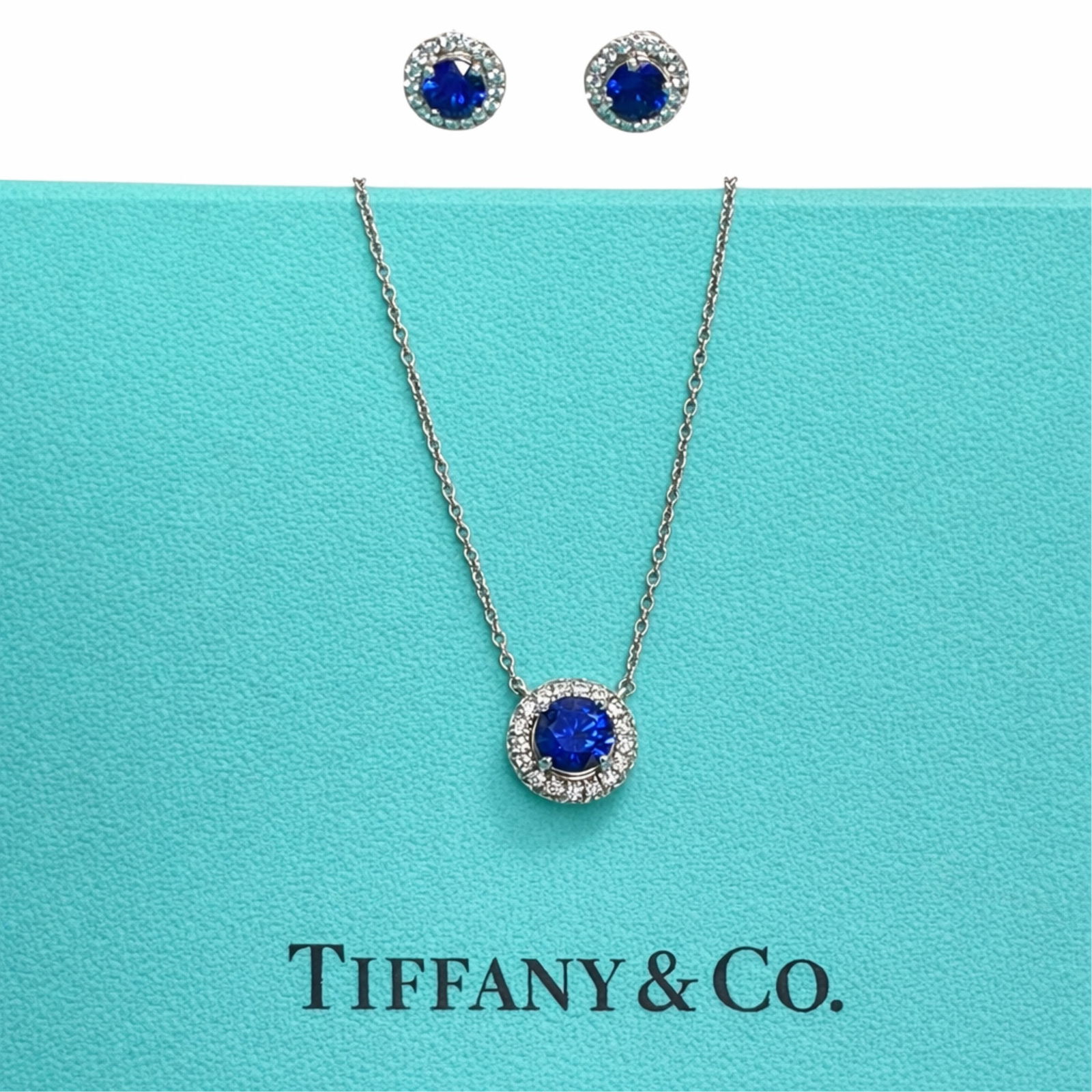 TIFFANY & CO. SAPPHIRE PENDANT AND EARRINGS: Tiffany Soleste diamond and sapphire stud earrings and pendant set in platinum. Earrings have .80cts sapphires and .18cts diamonds. Pedant has 16" chain and .40ct sapphire surrounded by .09cts