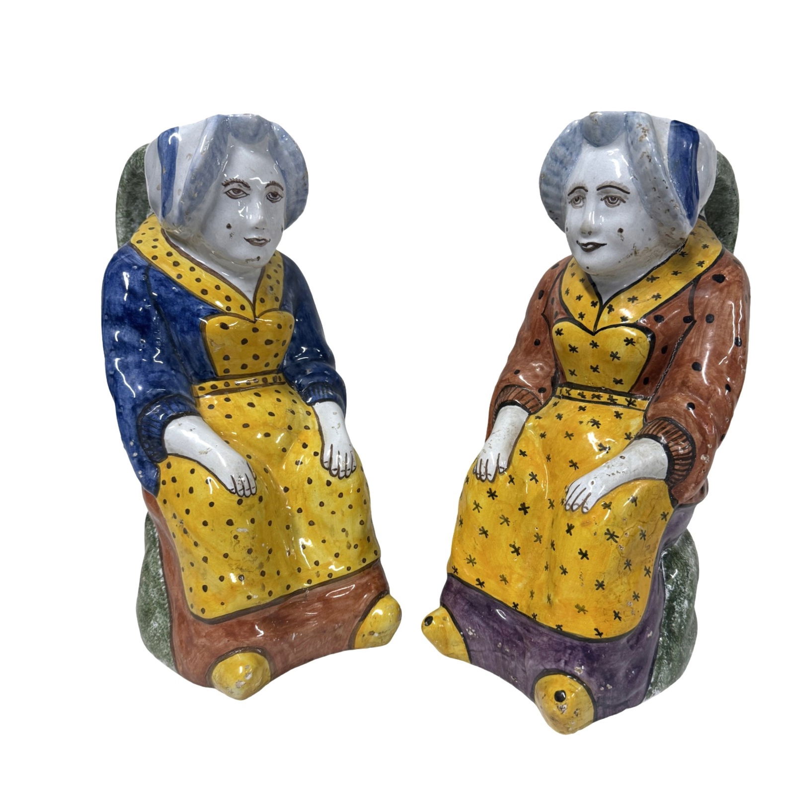 PAIR OF FAIENCE FIGURAL JUGS: Pair of hand painted French faience figural jugs depicting seated Breton women in traditional dress.