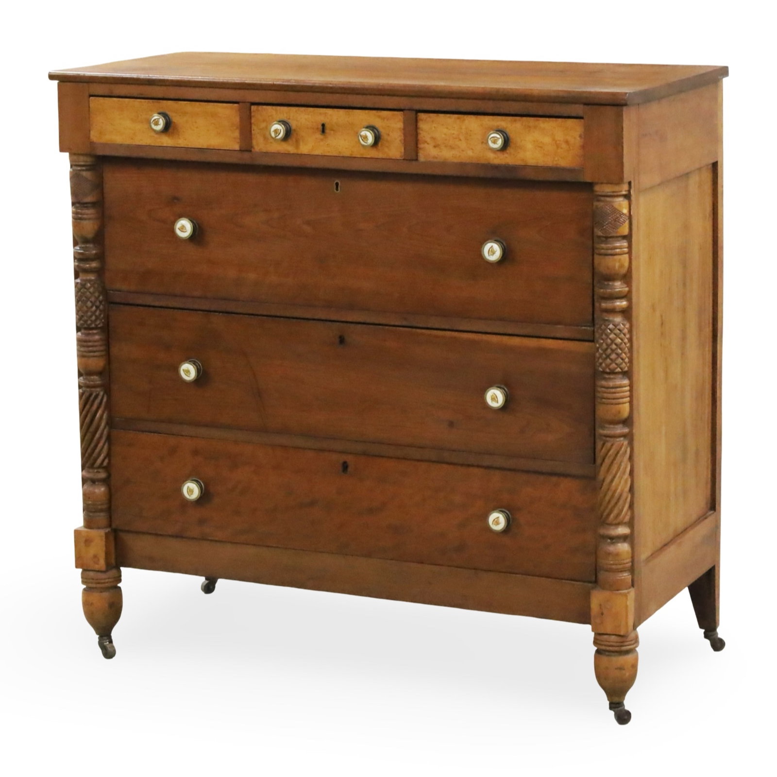 AMERICAN CHERRY AND BIRDSEYE MAPLE CHEST, 19TH C.: Fine American Empire cherry chest, straigth front, the frieze with three birdseye maple drawers, brass and enamel hardware with handpainted eagle motifs, turned columns with carved pineapple accents, 