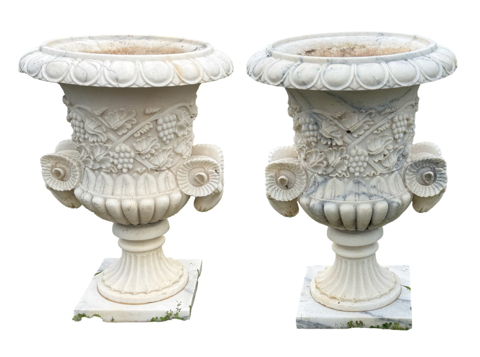 IMPRESSIVE PAIR OF CLASSICAL MARBLE GARDEN URNS: Large and impressive quality pair of Classical style variegated white marble garden urns, egg and dart carved lip, double rams head handles, the body with raised relief grape and leaf design, lowering