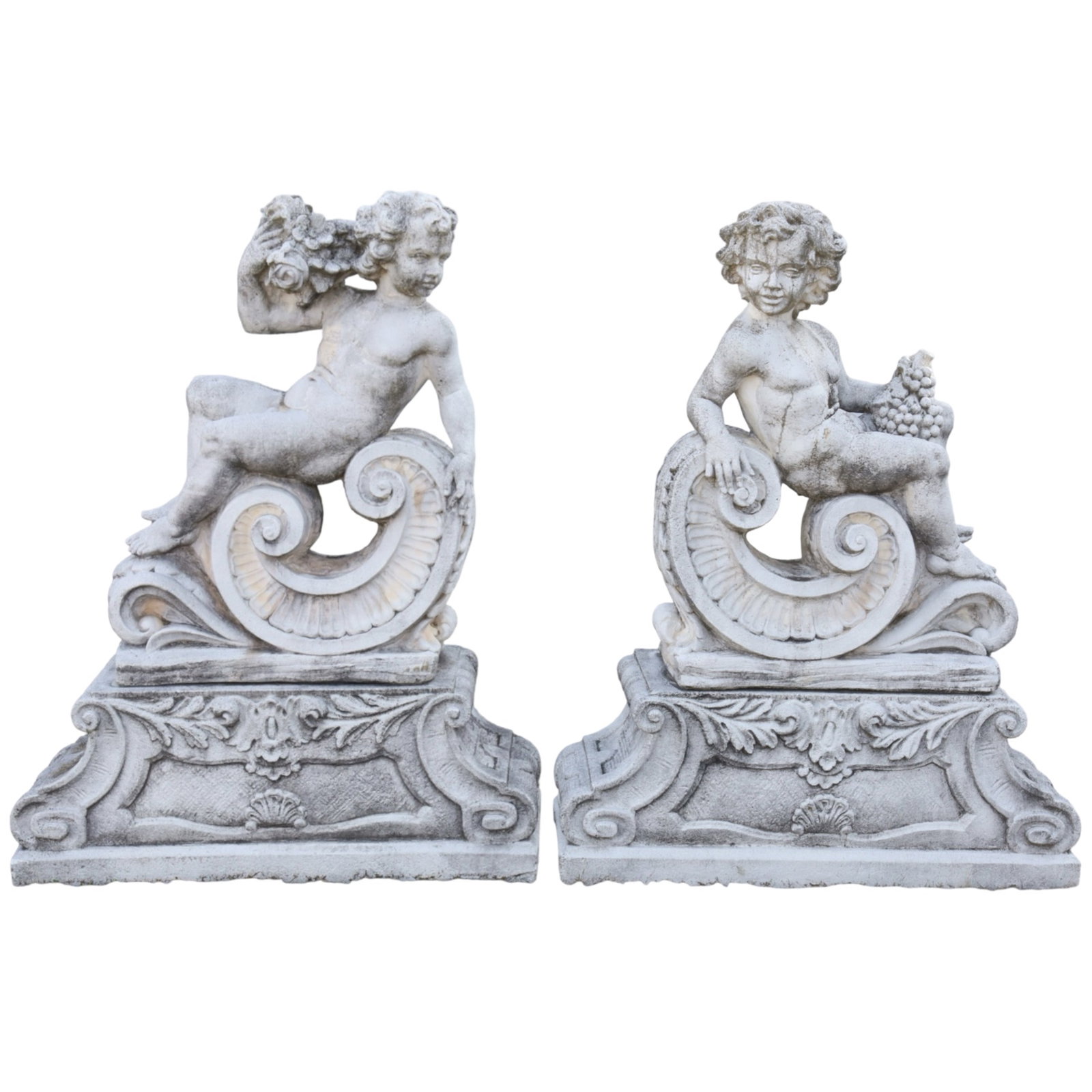 PR CAST STONE PUTTI GARDEN SCULPTURES: Pair of cast stone garden sculptures consisting on two putti holding flowers and grapes, representing the harvest seasons, the figures reclining on classical C scrolls atop conforming shaped plinths, 
