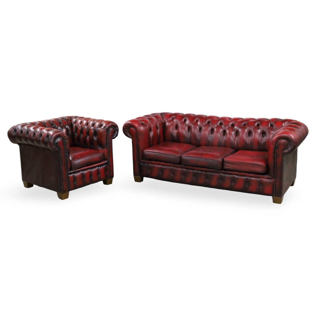 CHESTERFIELD LEATHER SOFA AND CLUB CHAIR: Tufted oxblood red leather Chesterfield sofa and matching club chair, both with rolled arms and brass nailhead trim, 20th century; sofa 29"H 77"W 33"D chair 29.5"H 38"W 32"D