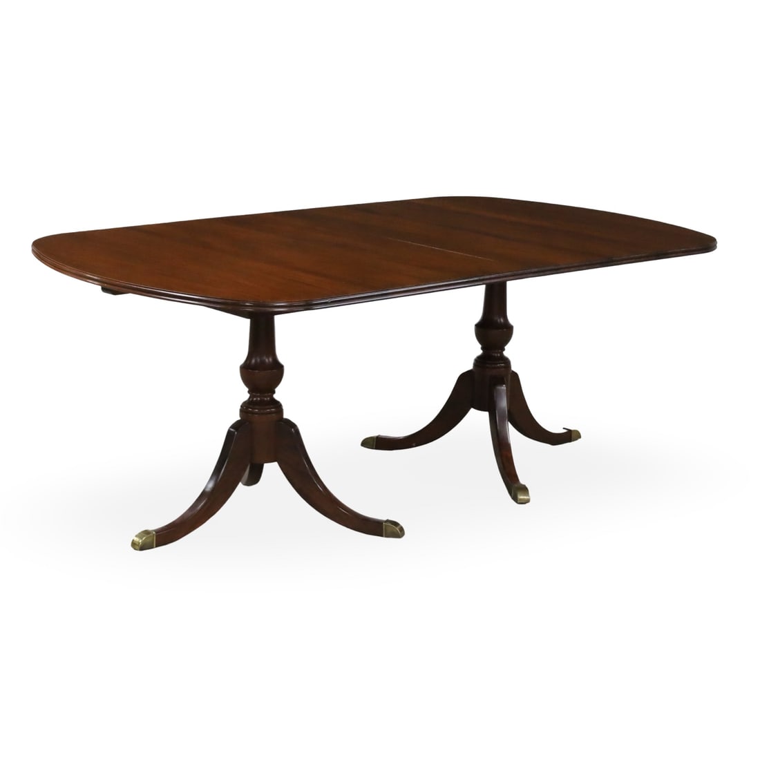 GEORGIAN STYLE MAHOGANY DINING TABLE: Georgian style mahogany dining table, double pedestal supports having trifid downswept legs with brass capped feet, including three 15" leaves; 30"H 45"W 77"L 122"L with leaves
