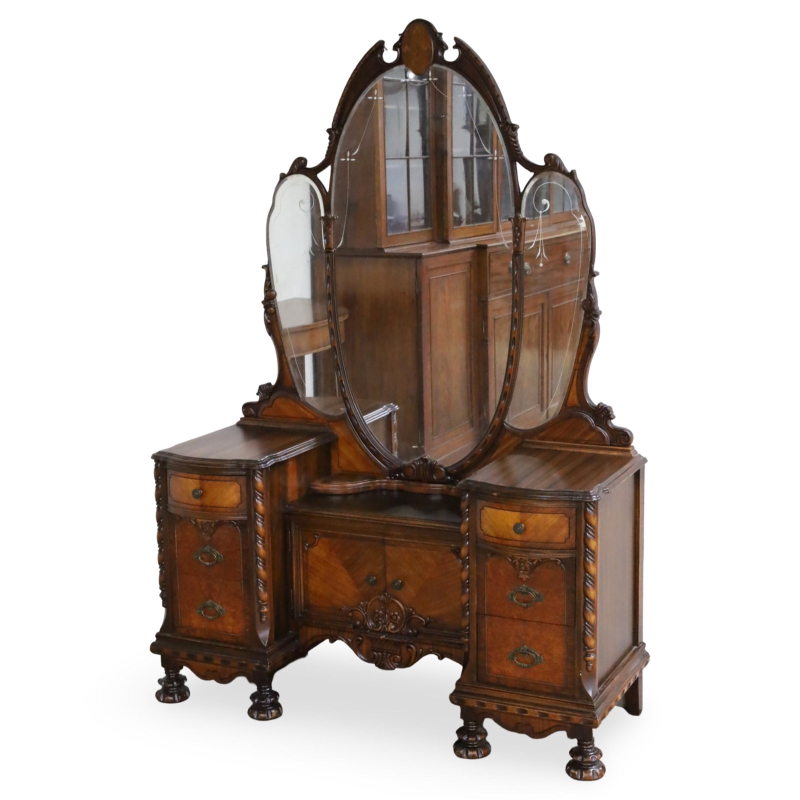 JACOBEAN REVIVAL VANITY: Jacobean Revival vanity having three part mirror, the walnut veneer case accented with braid and scroll moulding, 20th century; 75"H 50"W 18"D