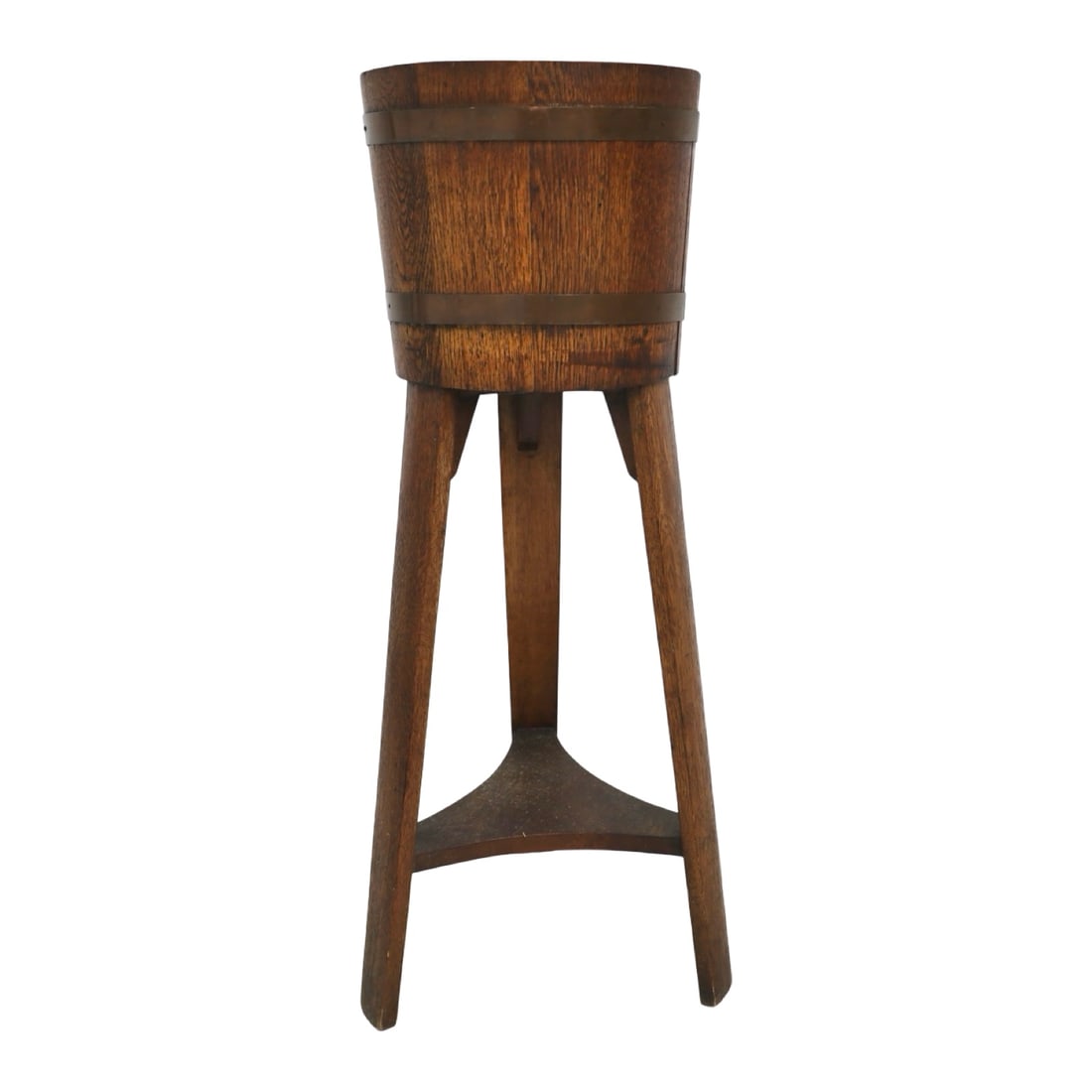 ARTS AND CRAFTS OAK COOPERED PLANT STAND: Arts and Crafts oak plant stand featuring a coopered barrel-form oak vessel with applied brass bands, raised on three tapered legs joined by shaped lower stretchers.12.5"W x 36"H