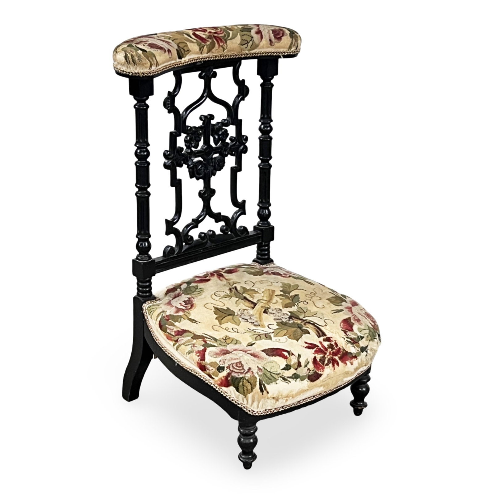 FRENCH OAK AND NEEDEPOINT PRIE DIEU: French oak prie dieu or prayer chair, ebonized frame with turned stiles and elaborately carved back rest, the crest rail and seat with floral needlepoint upholstery; 35.5"H 22"W 18"D