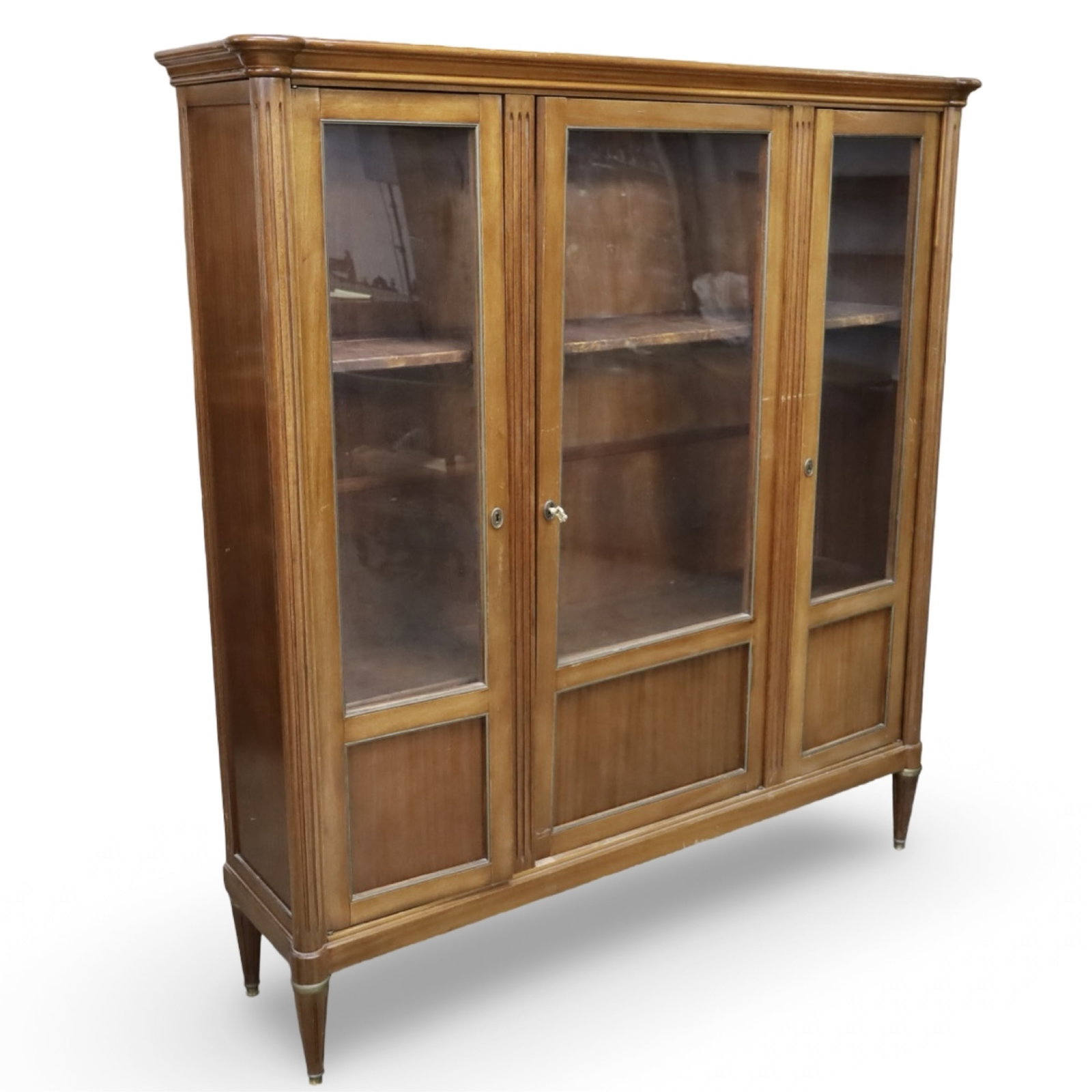 FRENCH PROVINCIAL WALNUT THREE-DOOR DISPLAY CABINE: French Provincial walnut three-door display cabinet with three doors opening to a shelved interior, molded cornice, and shaped base. Measures 64.5"W x 16"D x 71"H.