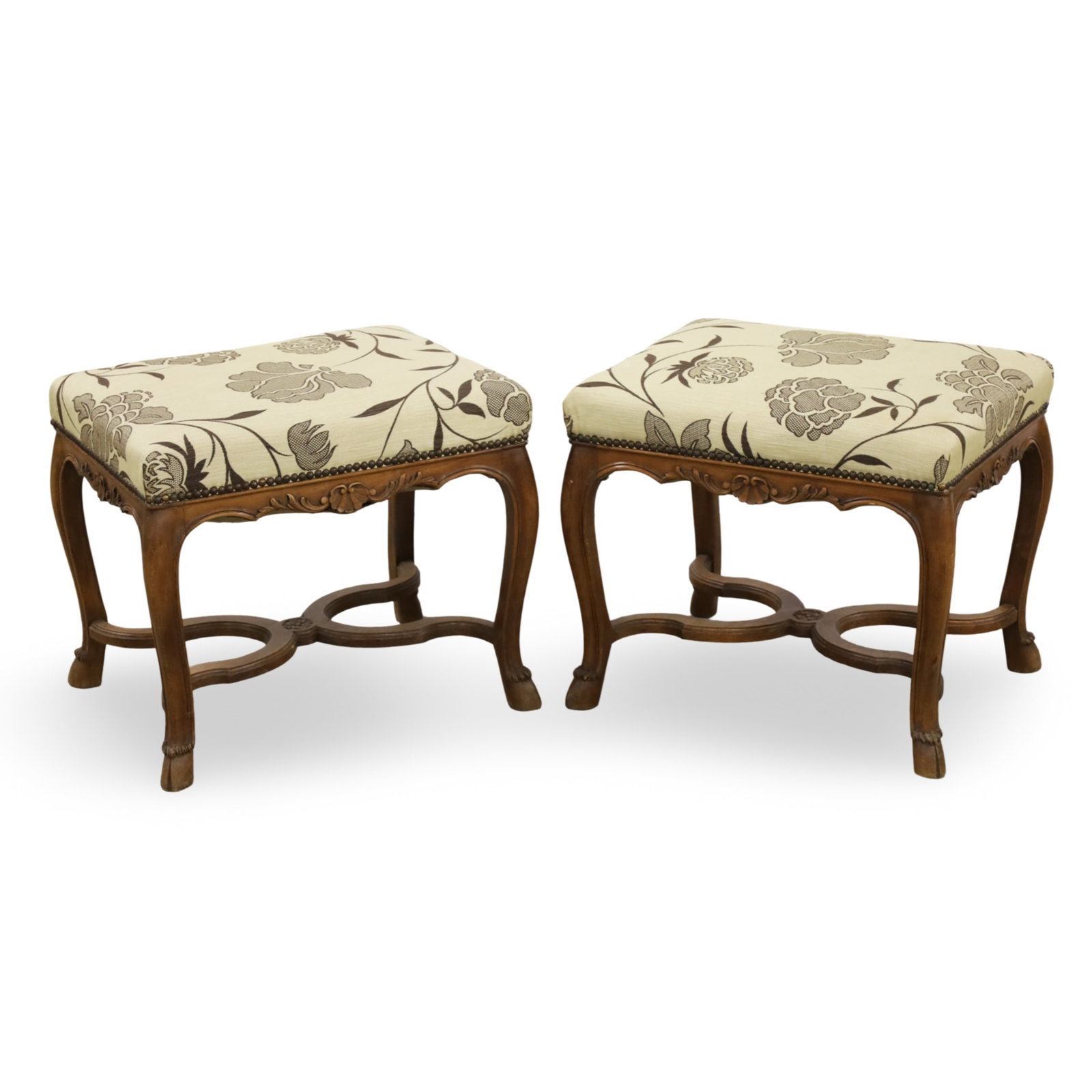 PR COUNTRY FRENCH WALNUT STOOLS: Pair of Country French stools featuring carved walnut frames with decorated aprons, resting on hoof feet, covered with floral pattern upholstery; 19"H 22"W 18"D