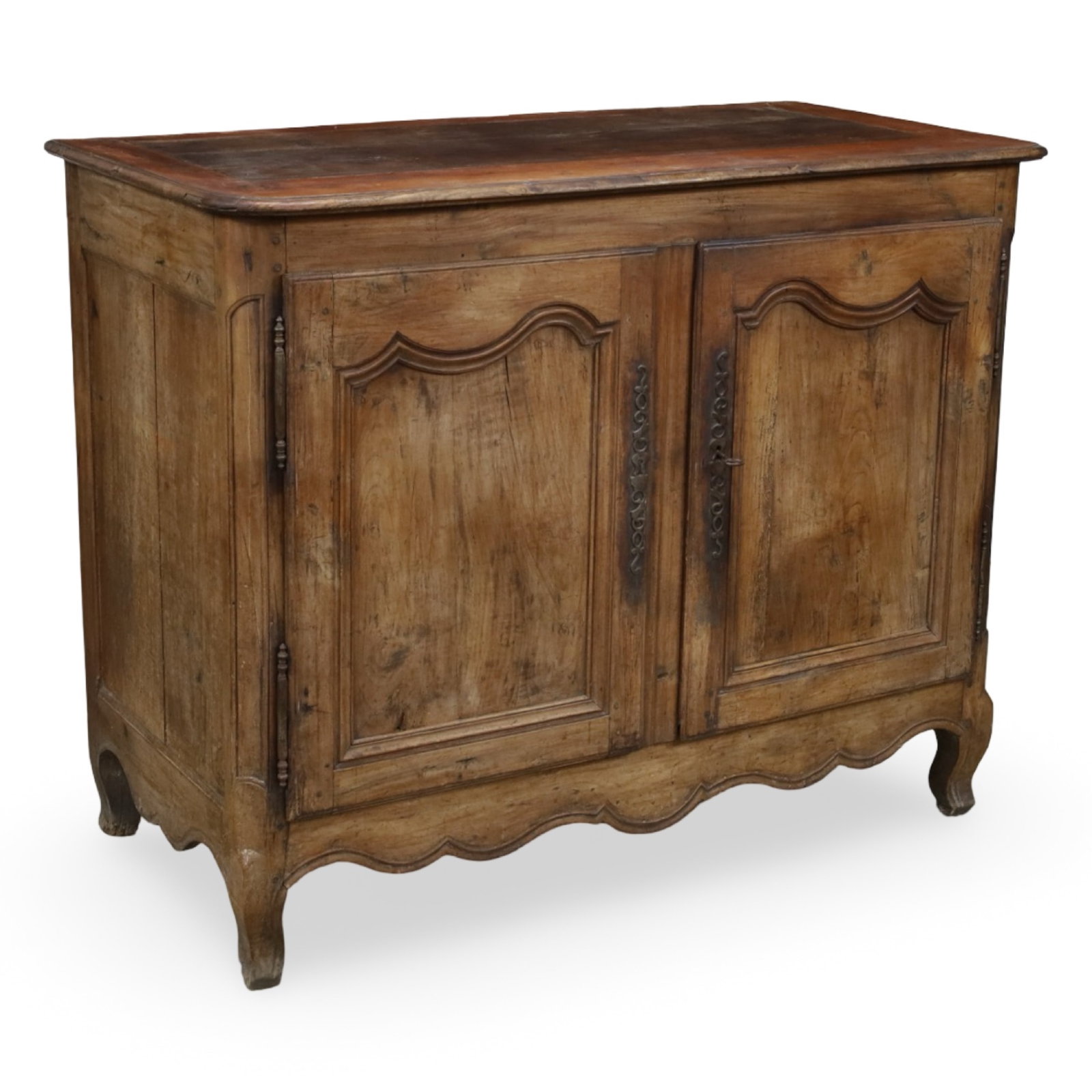 FRENCH PROVINCIAL WALNUT TWO-DOOR BUFFET: French Provincial walnut buffet having a rectangular plank top above two paneled doors with wrought iron escutcheons opening to a shelved interior, raised on shaped bracket feet with a scalloped