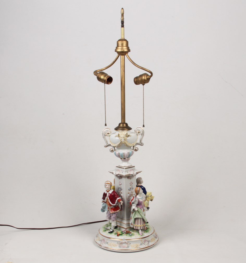 EUROPEAN HAND PAINTED PORCELAIN FIGURAL LAMP: EUROPEAN HAND PAINTED PORCELAIN FIGURAL LAMP HAVING RAM MOUNTED URN ON PEDESTAL SURROUNDED BY FESTIVE COSTUMED FIGURES OF 2 MEN AND 2 WOMEN; 35.5"H OVERALL; CONDITION: GIRL WITH WHEAT MISSING HAND, MA