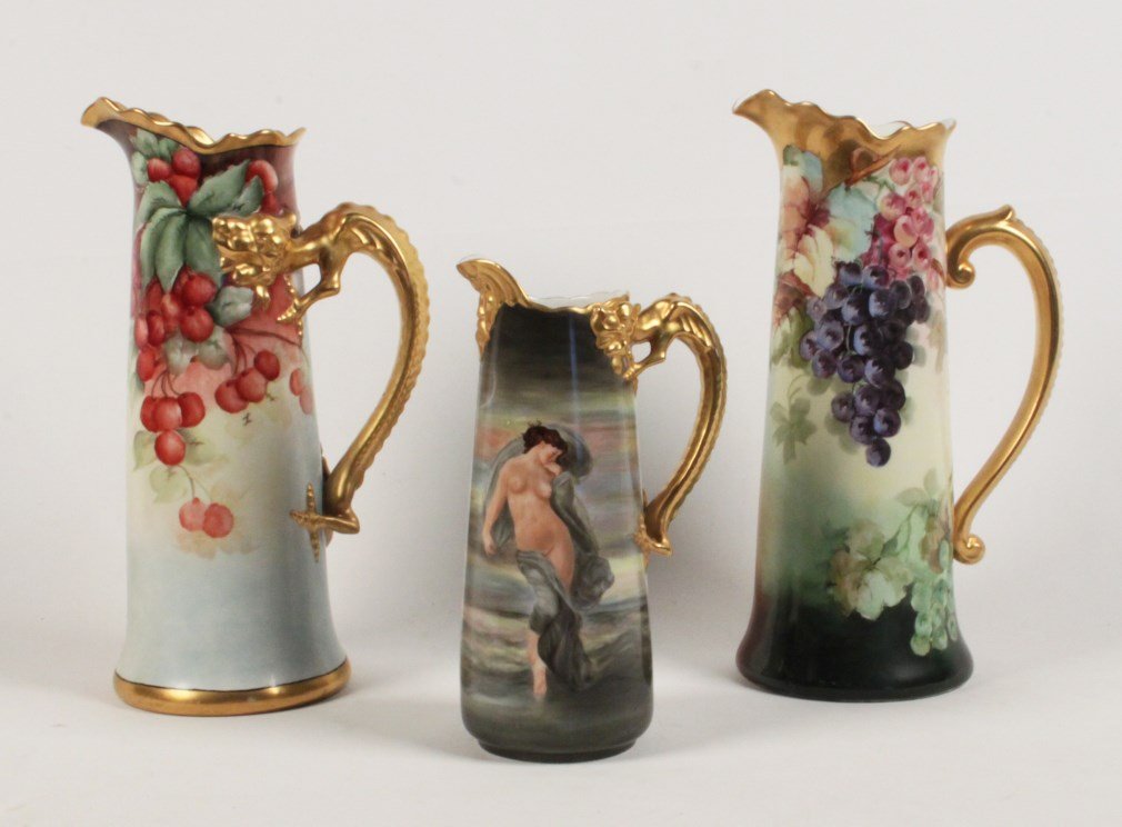 GROUP OF 3 HAND PAINTED LIMOGES PORCELAIN PITCHERS: GROUP OF 3 HAND PAINTED LIMOGES PORCELAIN PITCHERS, TWO WITH DRAGON FORMED HANDLES MARKED ON THE REVERSE "JPL FRANCE"; THE SMALLEST SIGNED LUCILLE OLIVE AND THE ONE WITH CHERRIES SIGNED DELLA; 15"H TA