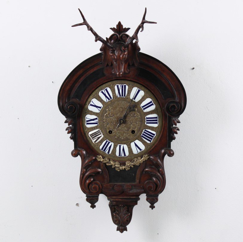 EUROPEAN CARVED WALNUT WALL CLOCK: EUROPEAN CARVED WALNUT WALL CLOCK WITH RAISED ENAMEL NUMERALS ON THE DIAL AND STAG HEAD MOUNT; 28"H X 17"W 5.25"D
