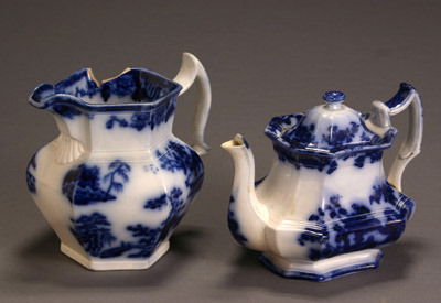 Charles Meigh Flow Blue 'Hong Kong' Pitcher and a: Charles Meigh Flow Blue 'Hong Kong' Pitcher and a 'Madras' Teapot The teapot with blue factory mark Madras/ J.T., possibly by John Thompson. Pitcher with large chip to rim and cracks; teapot with crac