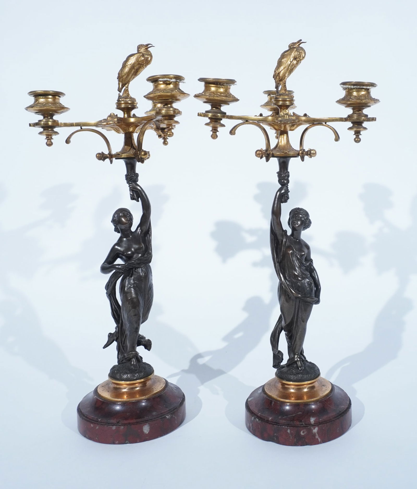 Pair of Napoleon III Ormolu Mounted Bronze Figural Three-Light Candelabra, Manner of Henri Picard,: Pair of Napoleon III Ormolu Mounted Bronze Figural Three-Light CandelabraManner of Henri Picard, Third Quarter 19th CenturyFastened to a mottled red marble plinth with stork finials.Provenance:Neal Au