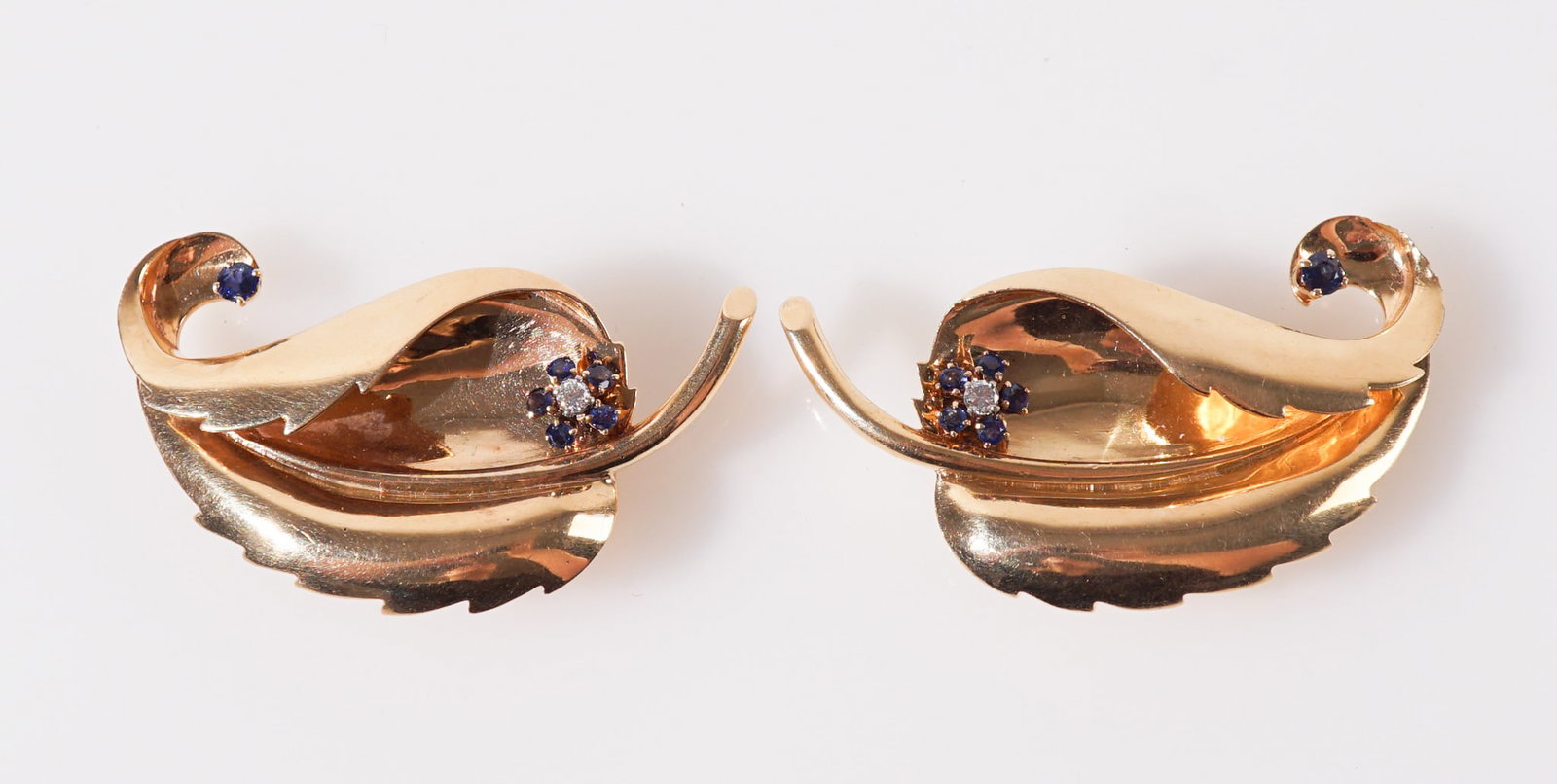 Pair of Retro 14-Karat Yellow-Gold, Diamond and Blue Sapphire Dress Clips, Circa 1940s, Total gross: Pair of Retro 14-Karat Yellow-Gold, Diamond and Blue Sapphire Dress Clips Circa 1940sEach curled leaf set with one round brilliant-cut melee diamond and six round faceted blue sapphires. Total gross w