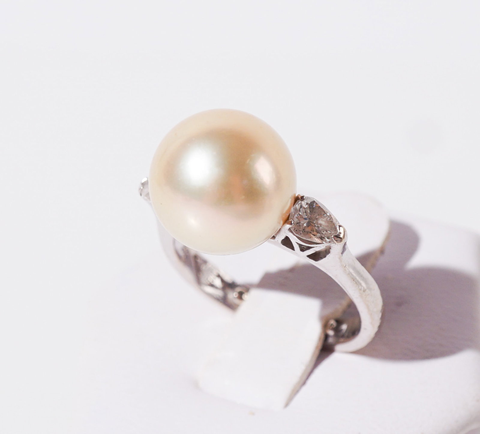 18-Karat White-Gold, Golden South Sea Pearl and Diamond Ring, Gross weight: 4.7 dwt., Shank size: 6: 18-Karat White-Gold, Golden South Sea Pearl and Diamond Ring Centered with one golden South Sea pearl measuring approximately 12 mm, flanked by two pear brilliant-cut diamonds weighing approximately .