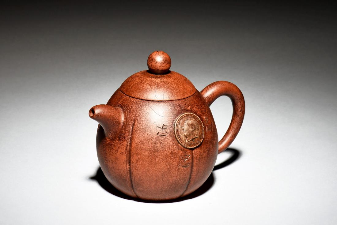 YIXING ZISHA 'CHAIRMAN MAO' TEAPOT: The Yixing Zisha teapot is of tall pear form, one side depicts a portrait of Chairman Mao Zedong, the other side with inscription, bottom bears mark. Height: 4 in (10.2 cm) Length: 5 1/2 in (14.0 cm) 