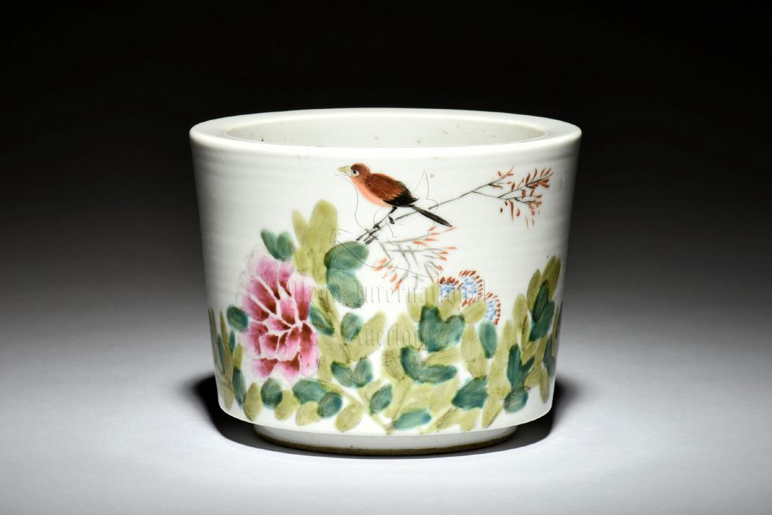FAMILLE ROSE 'BIRDS' BRUSH POT: The brush pot is of cylindrical form, the exterior painted in famille rose with flowers and birds, reverse with colophon, bottom bears four character mark. Height: 4 in (10.2 cm) Diameter: 5 in (12.7 