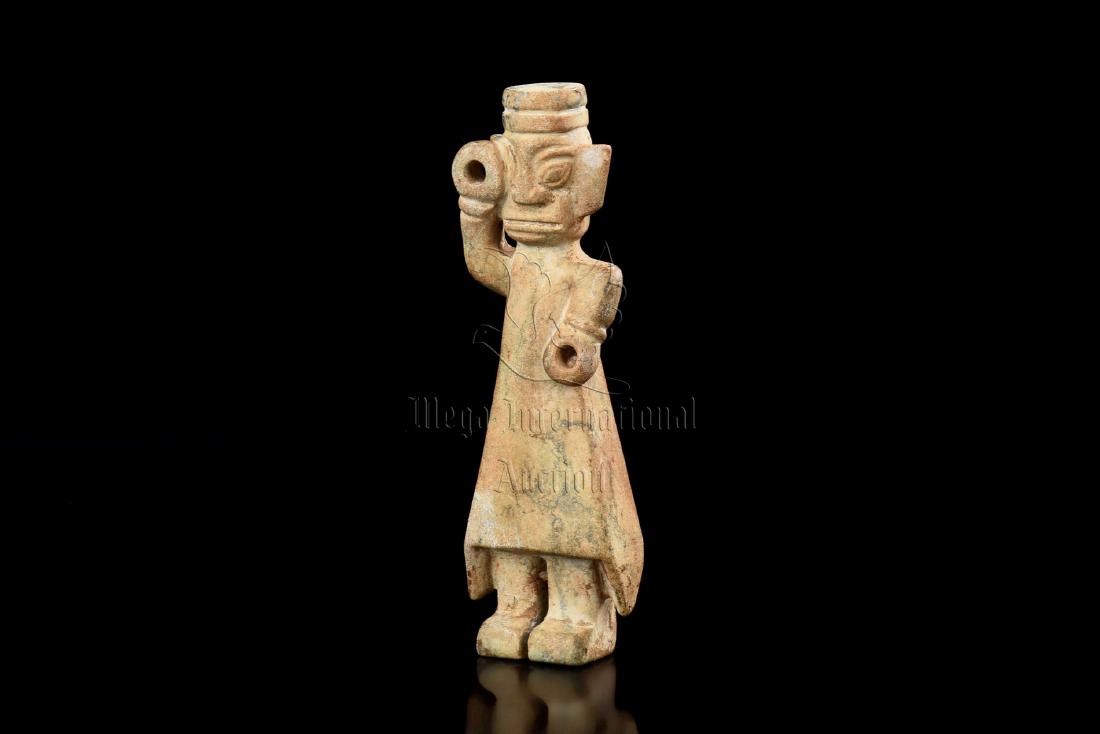JADE CARVED 'PERSON' FIGURE: The jade figure carved in the form of a standing man wearing long robe, one hand raised at eye level, the jade is of celadon and russet color tone. Height: 4 5/8 in (11.7 cm) 三星堆&