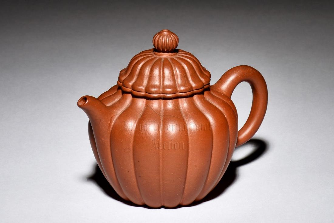 YIXING ZISHA LOBED TEAPOT: The Yixing Zisha teapot is of bulbous form with lobed exterior similar to chrysanthemum flower petals, the clay is of orange-brown color tone, complete with en-suite lid and finial, marks on the botto