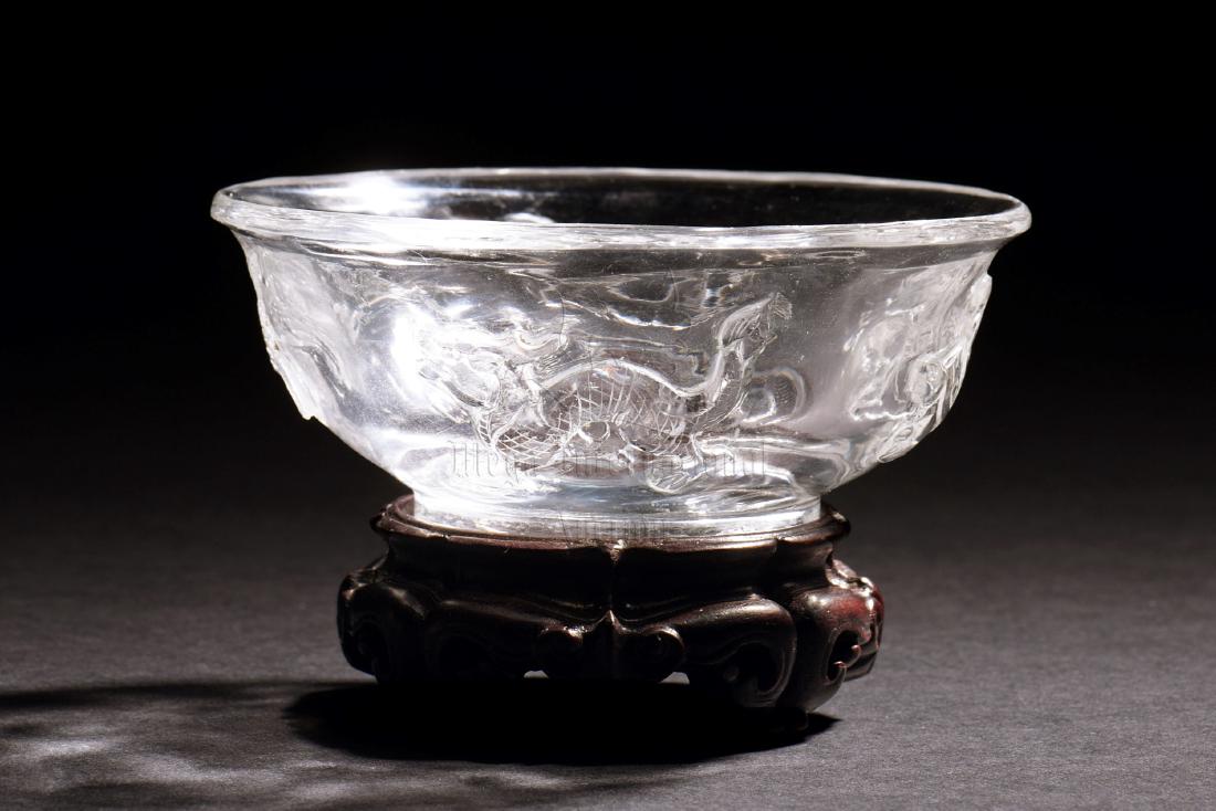 CRYSTAL 'FOUR SYMBOLS' BOWL WITH STAND: The crystal bowl depicts the Four Symbols on the exterior, including Azure Dragon, Vermillion Bird, White Tiger, and Black Turtle, all set on wooden stand. Height: 1 3/4 in (4.4 cm) Diameter: 4 1/8 in