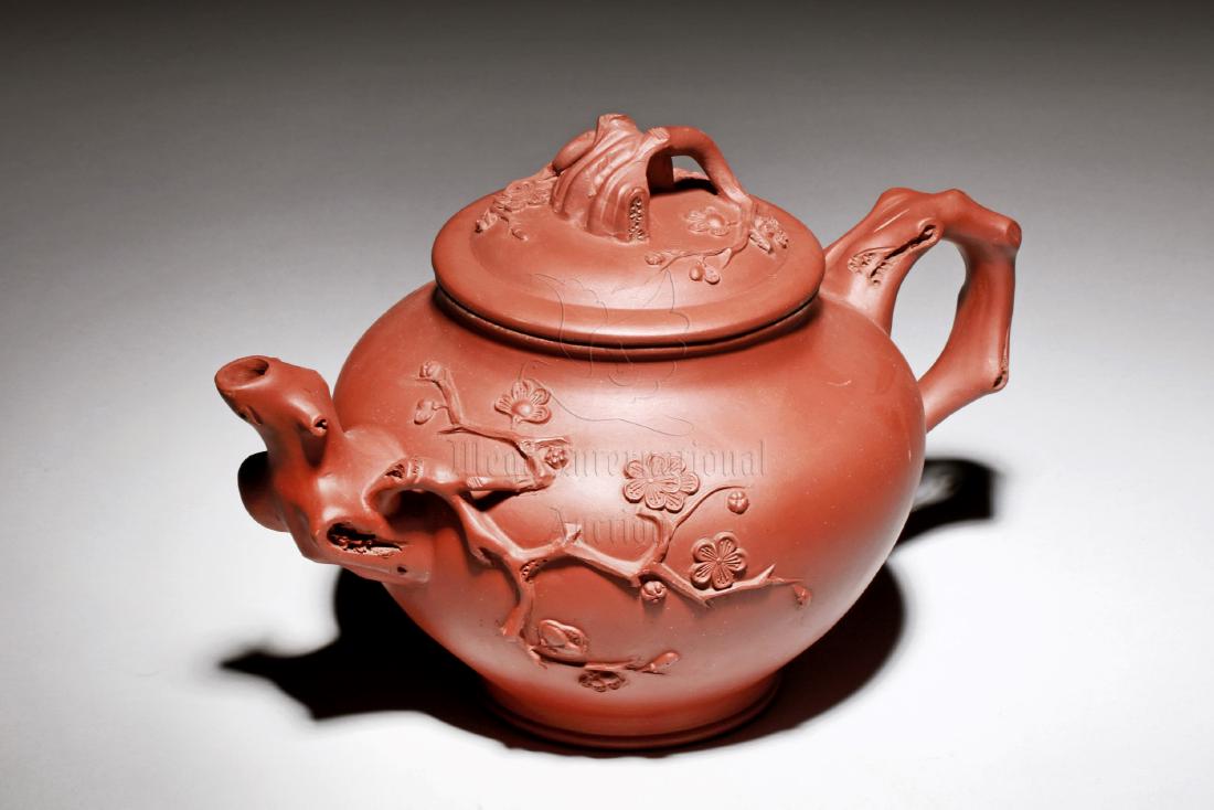 YIXING ZISHA 'PLUM FLOWERS' TEAPOT: The Yixing Zisha stoneware teapot is of bulbous form, the body depicts naturalistic plum flowers and branches, with branch shaped spout, handle, and finial, the clay is of brown color tone, and the te