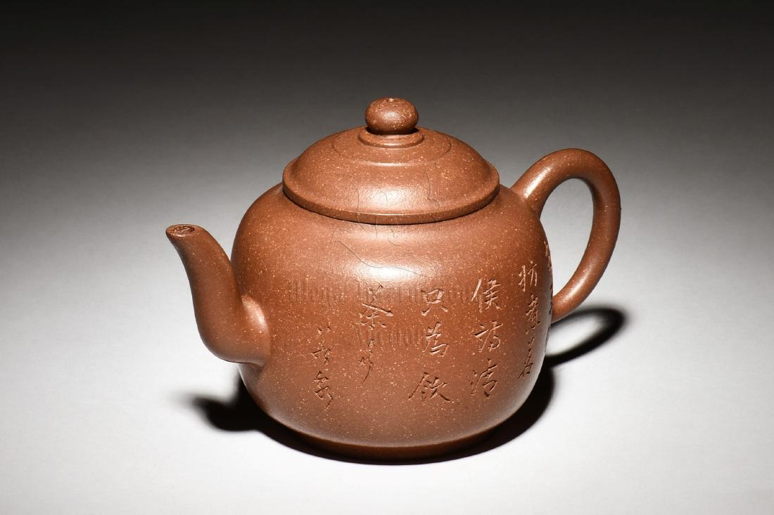 YIXING ZISHA 'POETRY CALLIGRAPHY' TEAPOT: The Yixing Zisha stoneware teapot is of bulbous form, the body incised with poetry calligraphy on the side, with elegant spout and handle below domed lid, the clay is of speckled dark brown color tone