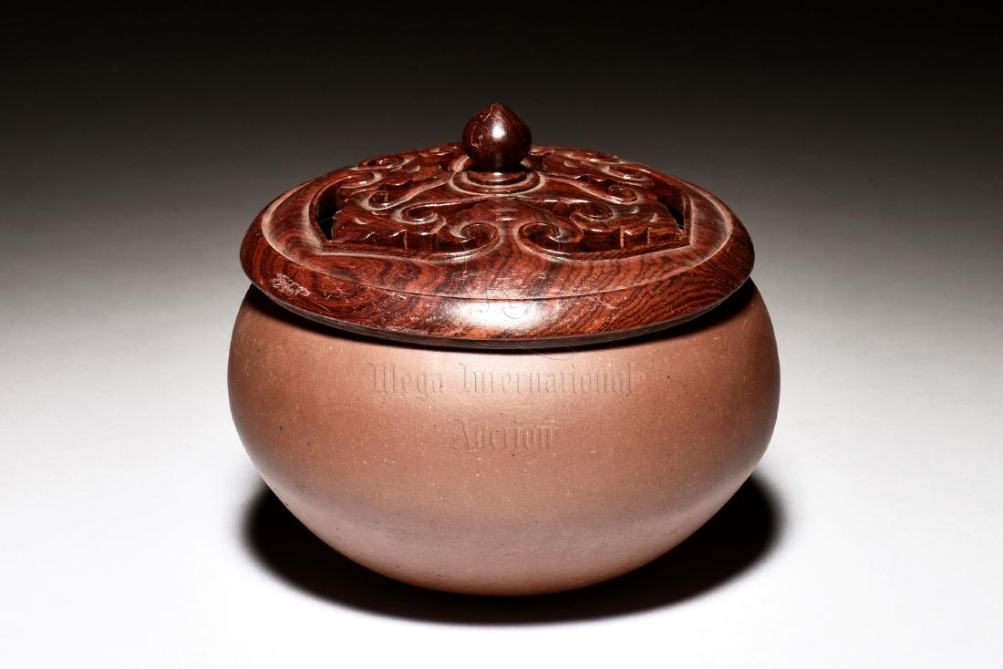 YIXING ZISHA JAR WITH COVER, BO: The Yixing Zisha bo jar is of bulbous form, the clay is of dark brown color tone, complete with openwork carved wooden lid. Height: 3 1/4 in (8.3 cm) Diameter: 5 3/4 in (14.6 cm) 紫砂Ņ