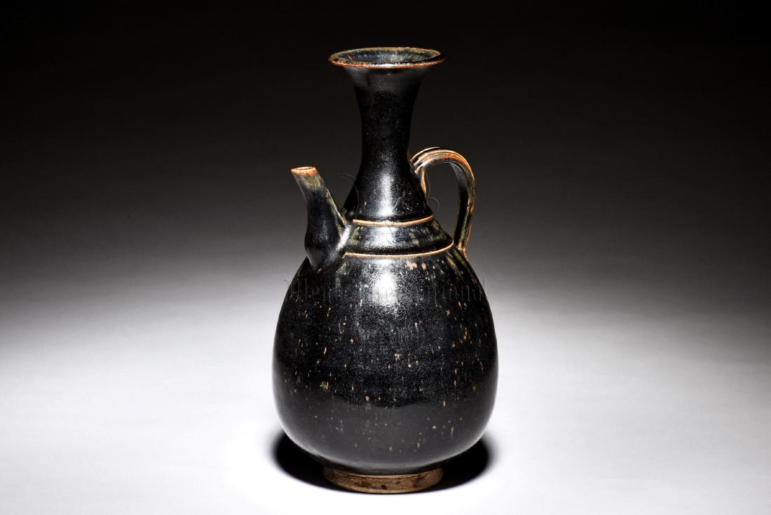CIZHOU WARE BLACK GLAZED WINE EWER: The Cizhou ware wine ewer has ovoid body, waisted neck, and evert rim, with small raised spout and C shaped handle on the shoulder, exterior glazed in deep black, bottom unglazed. Height: 11 1/4 in (2