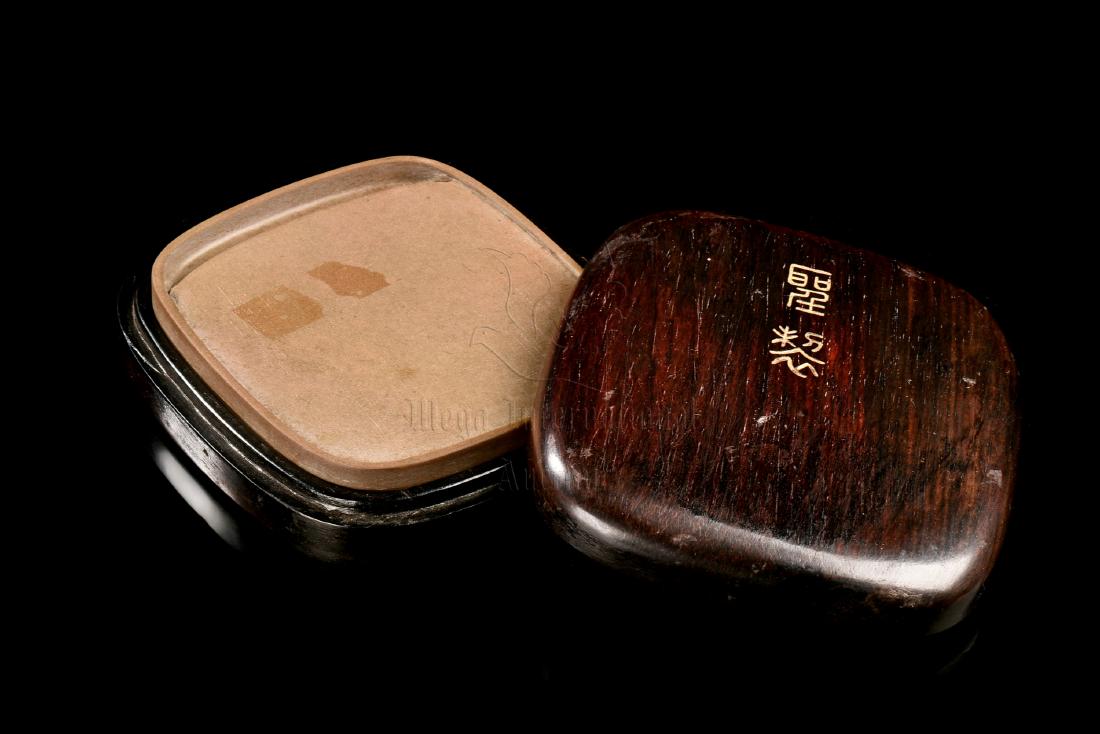 INKSTONE WITH INSCRIPTION AND WOODEN BOX: The inkstone is of flattened rounded rectangular form, one side with shallow inkwell, reverse incised with calligraphy and marks, the stone is of light brown color tone, set in en-suite wooden box wit