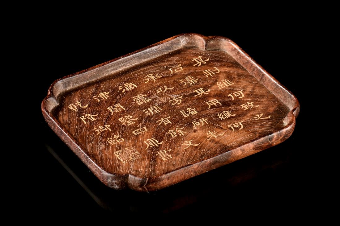 ZITAN WOOD CARVED 'CALLIGRAPHY' DISH: The zitan wood dish carved with curved edges, center incised with poetry calligraphy and mark, the wood retains natural grain, color, and patina, bottom bears three character mark. Length: 4 3/4 in (1