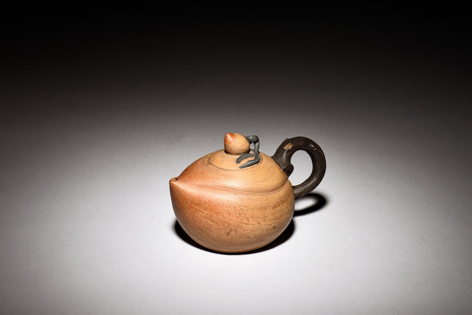 YIXING ZISHA 'PEACH' TEAPOT: 紫砂桃形茶壺 The Yixing Zisha teapot is of globular form, shaped similar to a large peach, with vine shaped handle and small peach finial, the clay is of light brow
