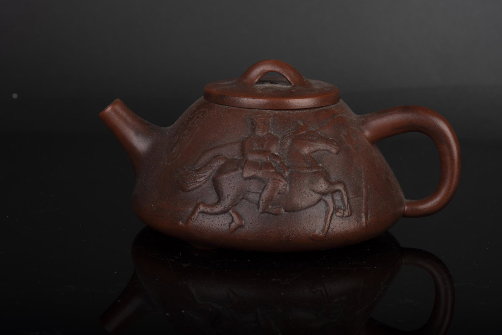 YIXING ZISHA CARVED 'HORSE RIDER' TEAPOT: 紫砂人物茶壺 Yixing Zisha carved 'Horse Rider' teapot Height: 3 in (7.6 cm) Width: 6 in (15.2 cm)