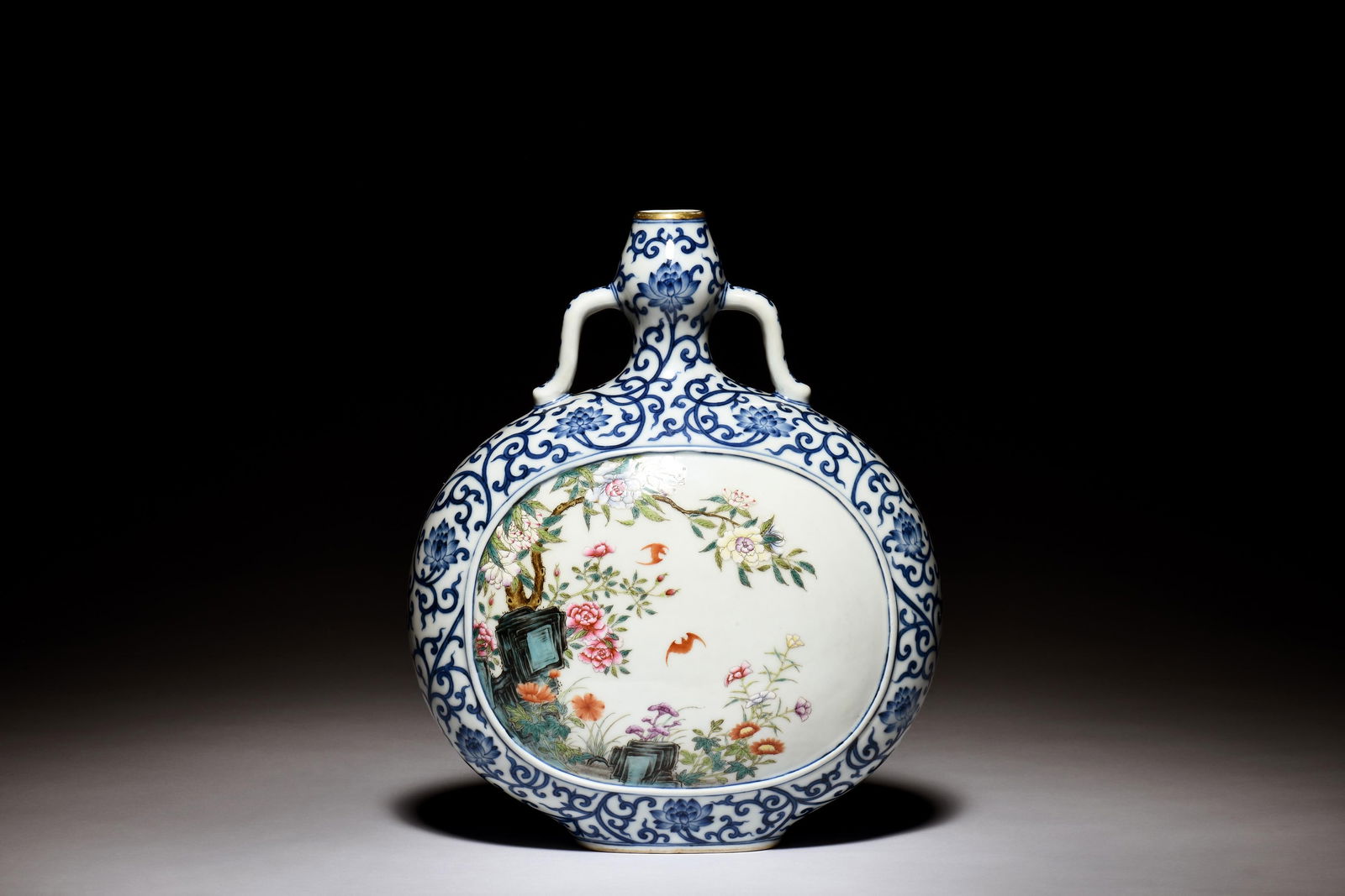 BLUE AND WHITE AND FAMILLE ROSE 'FLOWERS' MOONFLASK: 青花底開光粉彩花卉扁瓶 The blue and white moon flask vase is of flattened ovoid form, body depicts famille rose flowers and bats in ce