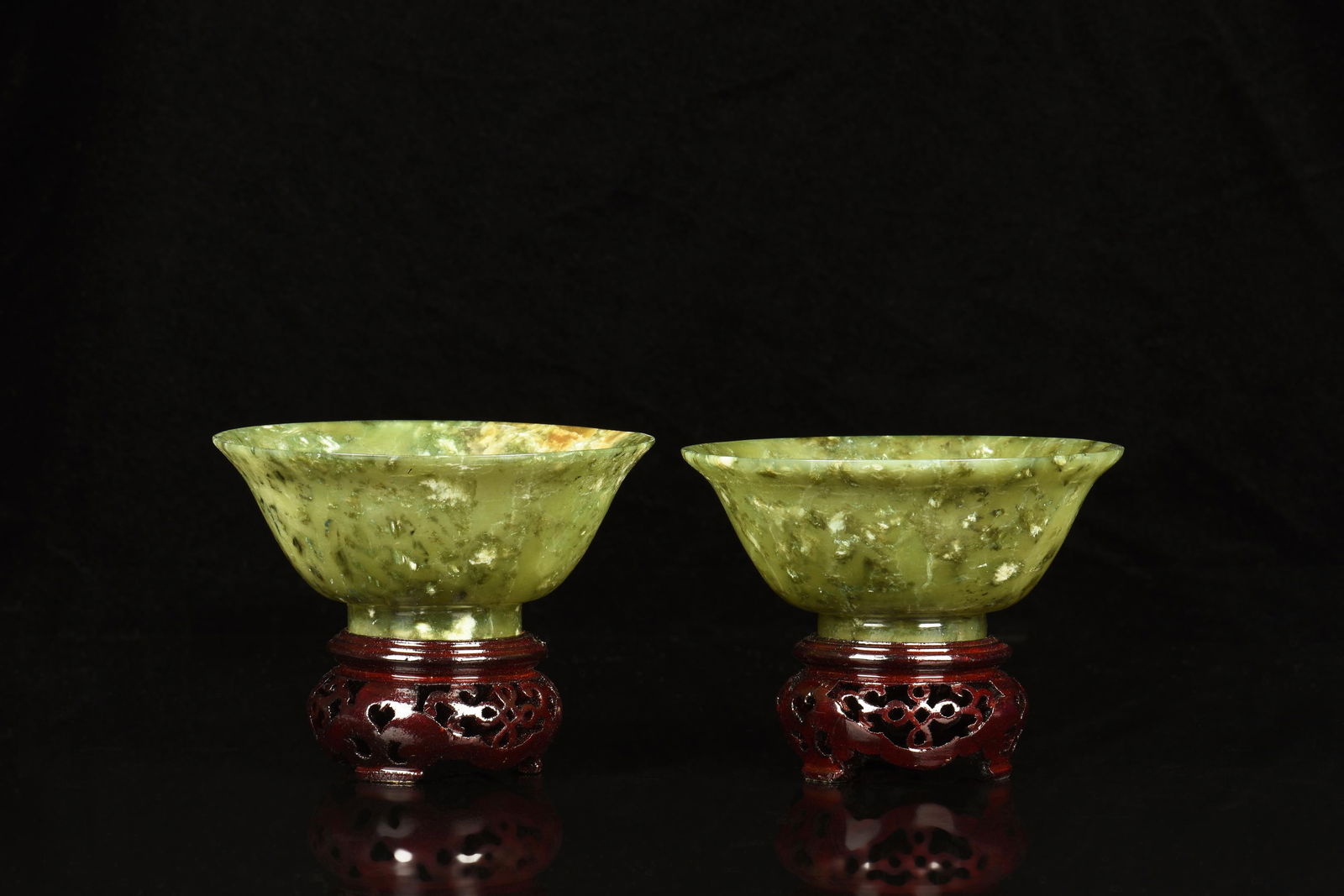 PAIR OF JADE CUPS WITH STANDS: 青玉碗一對 The well-carved jade cups set on pierce carved wooden stands, the jade is of yellowish-green color tone with mottled interior and russet. PAIR OF JADE CUPS WIT
