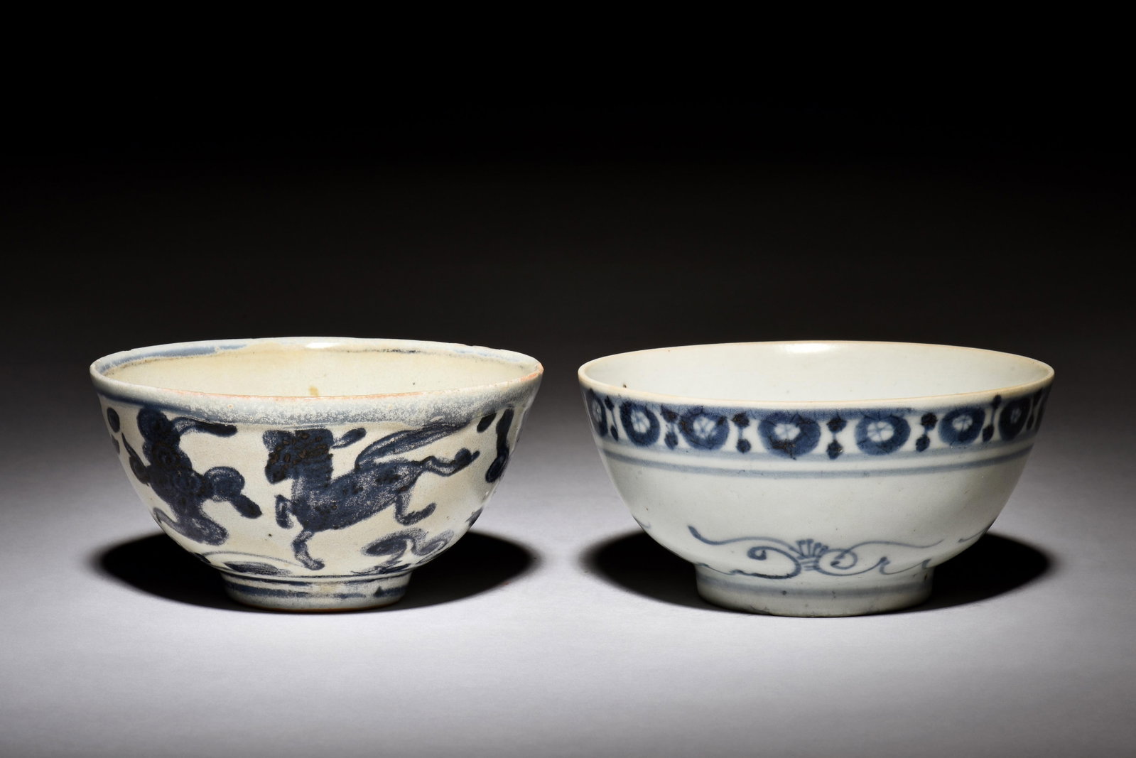 TWO BLUE AND WHITE BOWLS: 青花小碗兩個 The lot includes two similarly sized and shaped blue and white bowls, one depicts mythical beast flying amidst clouds, bottom bears four character DA M