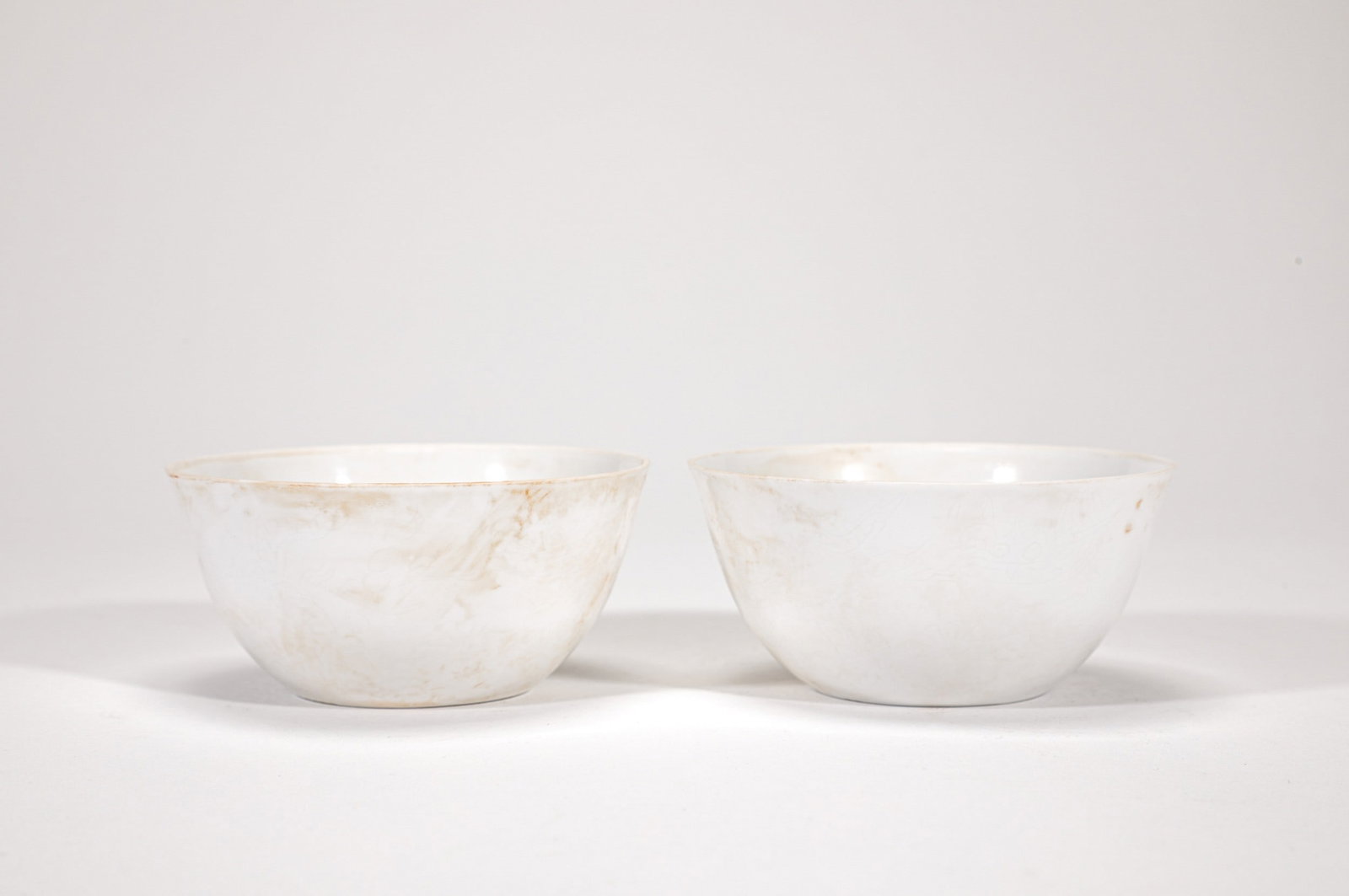 A PAIR OF WHITE GLAZED DRAGON CUPS: 明永乐白釉暗刻龙纹杯一对 A pair of white glazed dragon cups Diam.8cm Ht.4cm