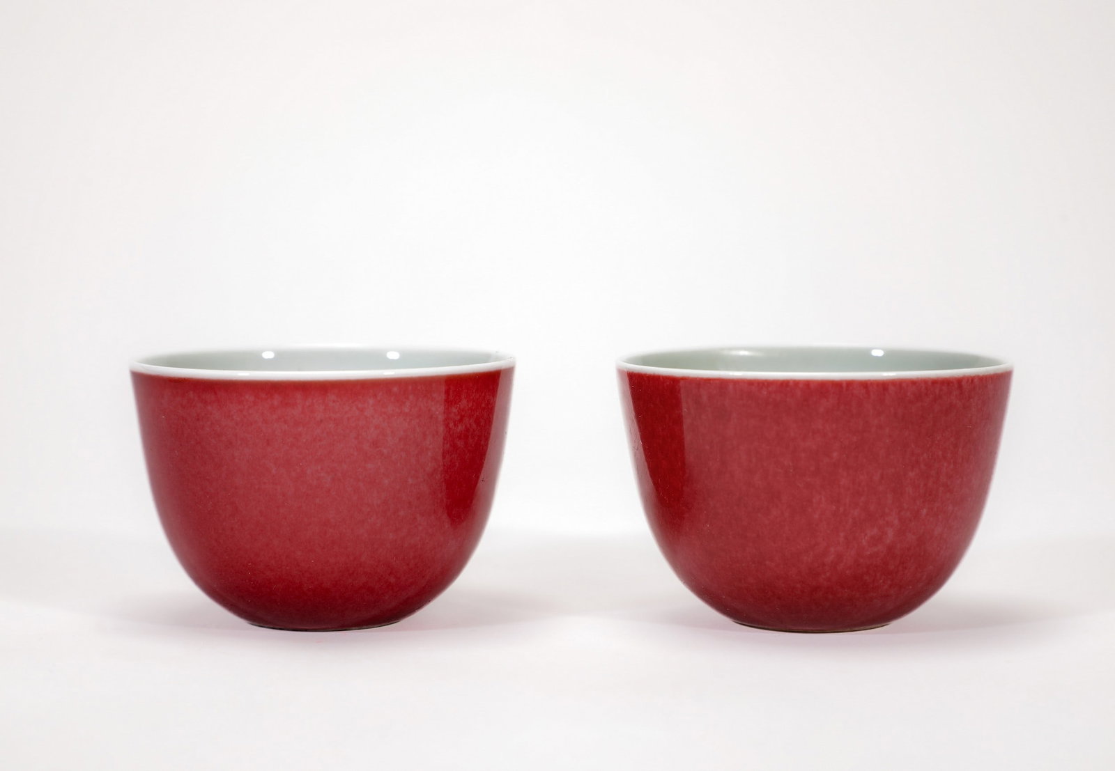 A PAIR OF RED GLAZED CUPS: 清雍正红釉卧足杯一对 A pair of red glazed cups Diam.6.5cm Ht.4.5cm