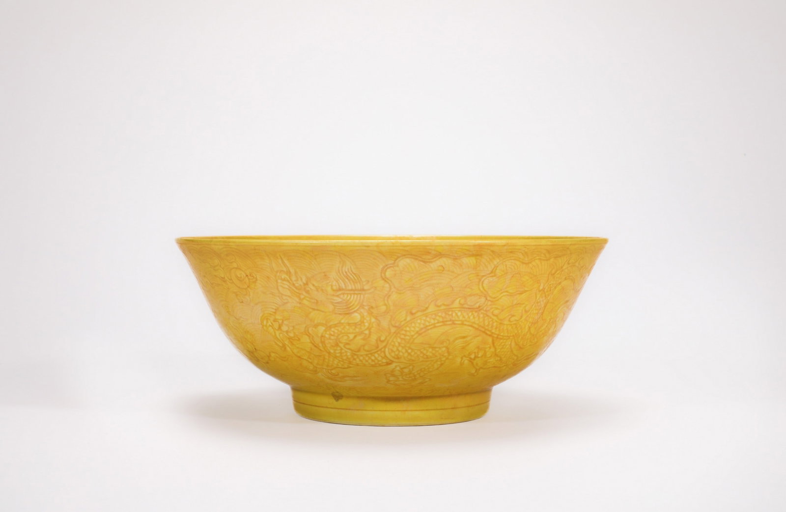 A YELLOW GLAZED DRAGON BOWL: 明成化黄釉暗刻海水龙纹碗 A yellow glazed dragon bowl Diam.18.5cm Ht.7.5cm