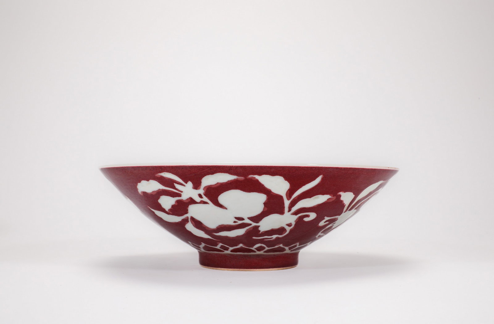 A RED GLAZED FRUIT BOWL: 明宣德红釉留白花果纹碗 A red glazed fruit bowl Diam.23cm Ht.7.5cm