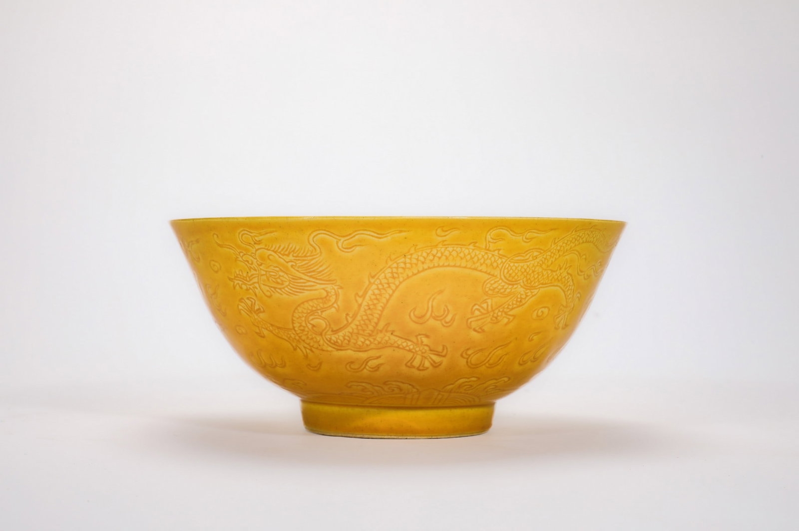A YELLOW GLAZED DRAGON BOWL: 清康熙黄釉暗刻云龙纹碗 A yellow glazed dragon bowl Diam.15cm Ht.7cm
