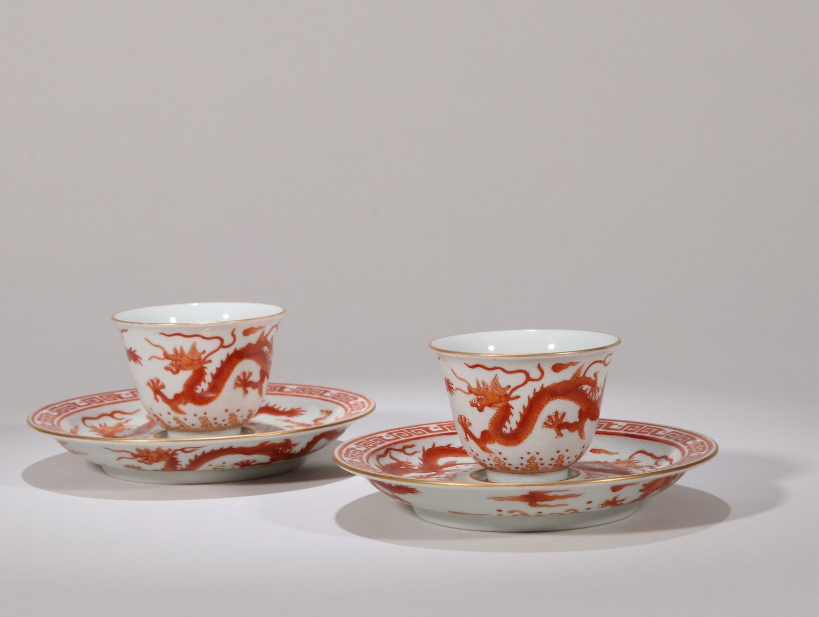 A SET OF IRON-RED DRAGON CUP AND DISH: 乾隆 矾红堆白云龙纹杯盏一套 A set of iron-red dragon cup and dish Diam.12cm