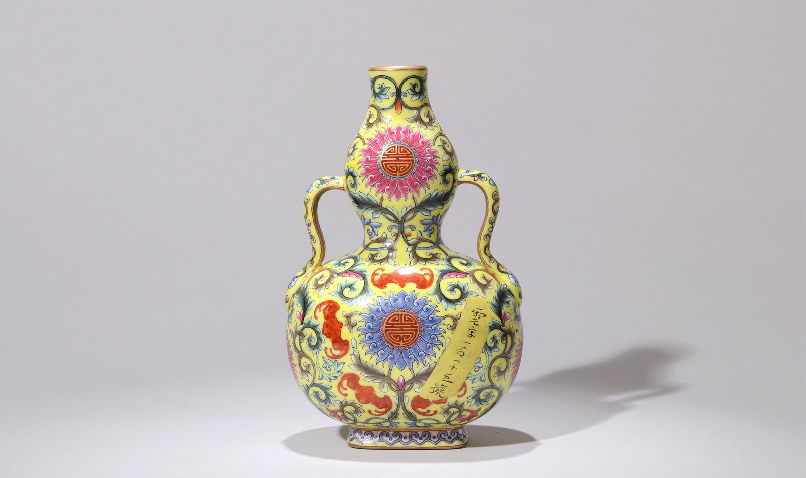 A YELLOW-GROUND FAMILLE-ROSE CALABASH MOONFLASK: 乾隆 黄地粉彩花卉葫芦扁瓶 A yellow-ground famille-rose calabash moonflask Ht.17cm