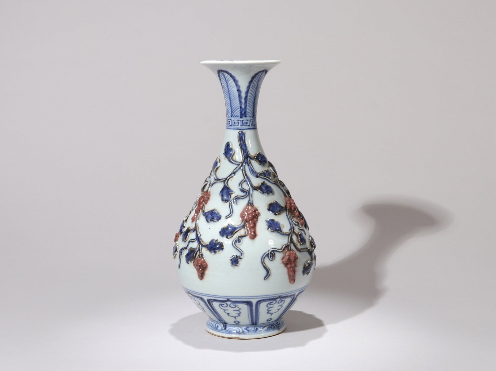 A BLUE AND WHITE COPPER-RED GRAPE VASE: 元 青花釉里红堆塑葡萄纹玉壶春瓶 A blue and white copper-red grape vase Ht.25cm