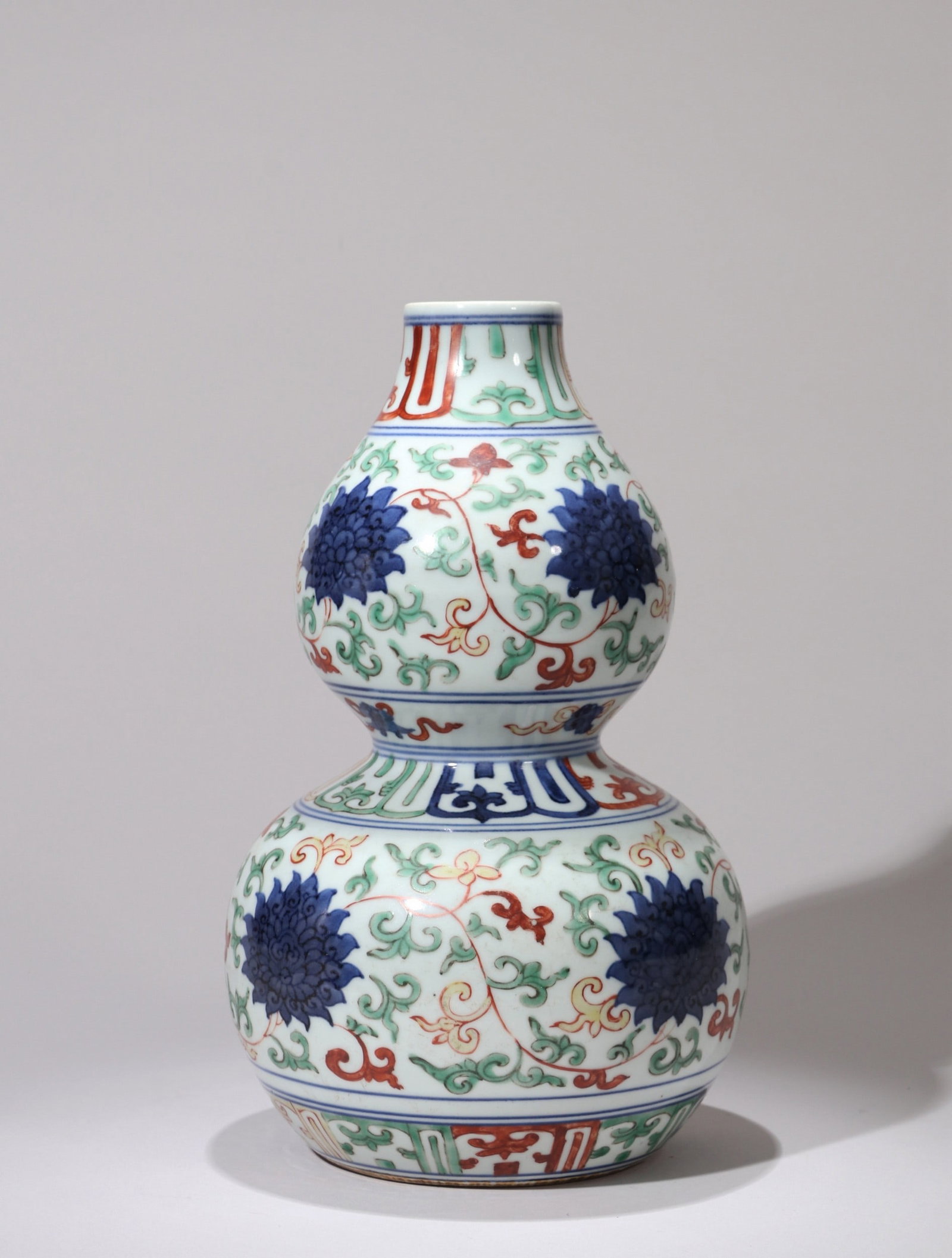 A BLUE AND WHITE WUCAI FLORAL DOUBLE-GOURD VASE: 隆庆 青花五彩花卉葫芦瓶 A blue and white wucai floral double-gourd vase Ht.25cm