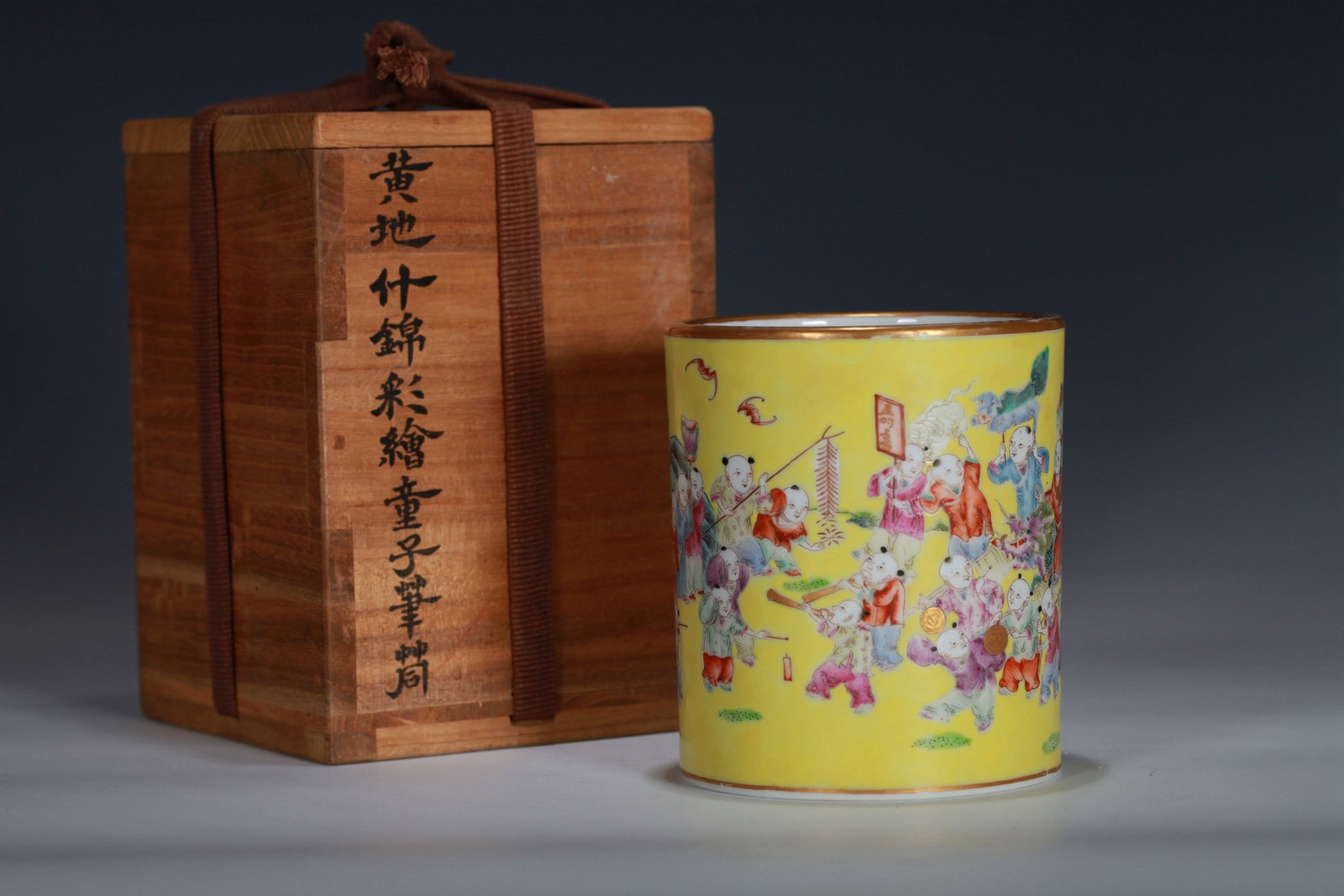 A YELLOW-GROUND FAMILLE-ROSE FIGURE BRUSH POT: 清 黄地粉彩婴戏纹笔筒 A yellow-ground famille-rose figure brush pot Ht.11CM Diam.9.5CM