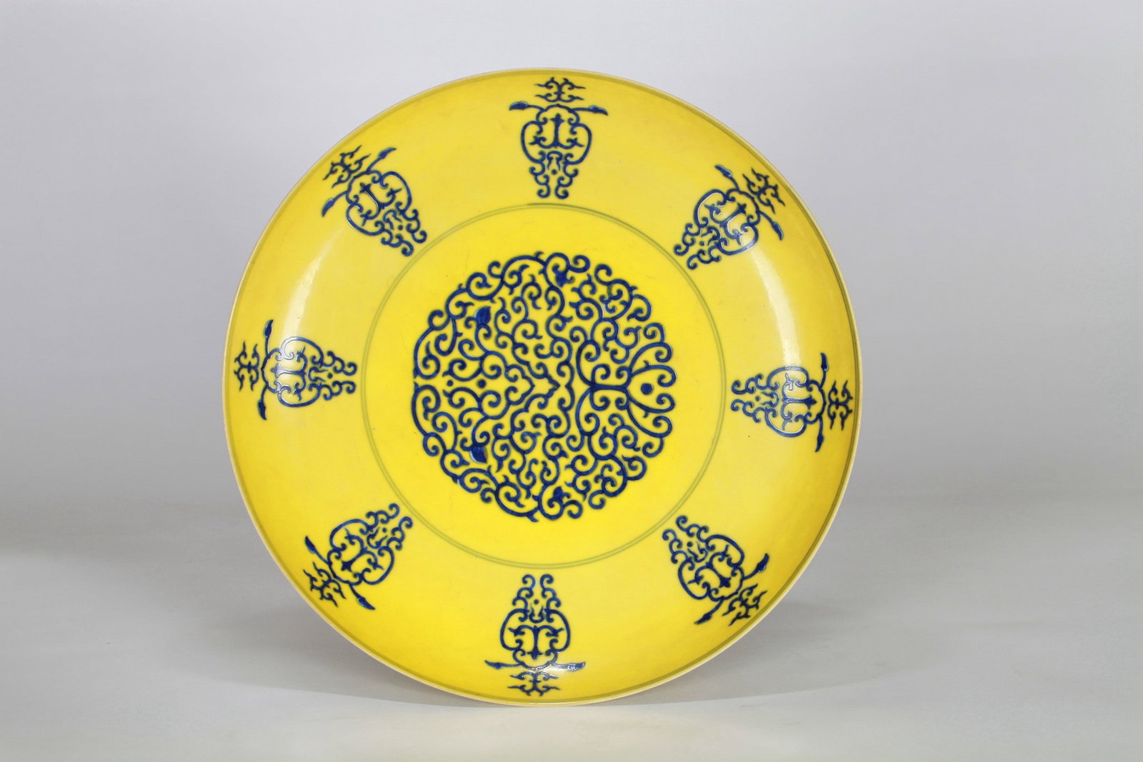 A YELLOW-GROUND BLUE AND WHITE FLORAL DISH: 清 黄地青花贯套纹盘 A yellow-ground blue and white floral dish Diam.30