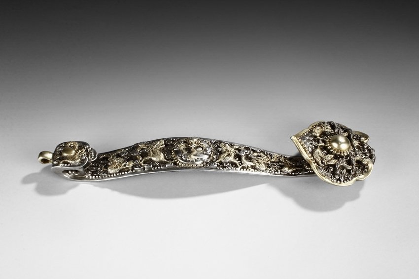 A GILT BRONZE 'DRAGONS' RUYI SCEPTER: The ruyi scepter, gold and silver gilt bronze, intricately carved with the nine dragons theme. The end of handle carved with a dragon circling around a flaming sphere, the handle carved with six drago