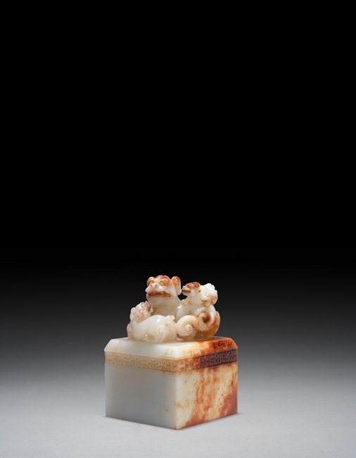 A CARVED WHITE JADE SEAL: This square-sectioned jade imperial seal is shown with the knob carved into three Buddhist lions and a continuous band of shallow relief Ruyi pattern on the sides. The seal base is carved with four ch