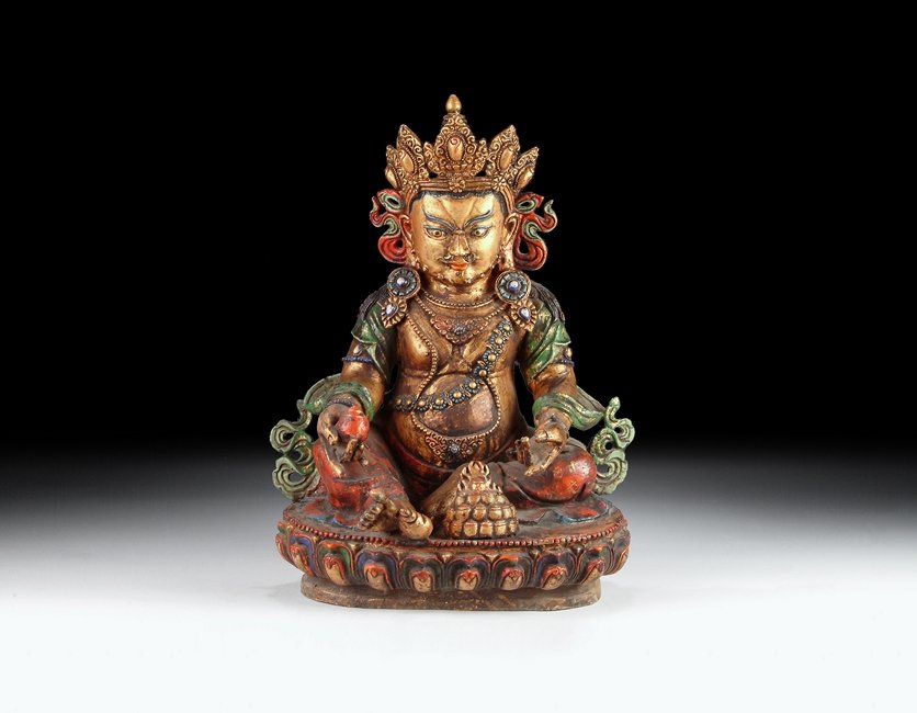 A TIBETAN GILT-BRONZE FIGURE OF YELLOW JAMBHALA: This gilt-bronze Tibetan deity is seated on a raised lotus throne, with one foot stretching out slightly. He is dressed in colorful and ornate clothes, completed with decorated headdress, earrings, ne